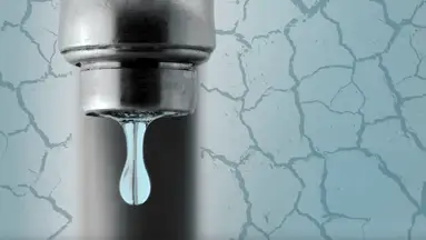 Pipe faucet dripping water surrounded by cracked ground.