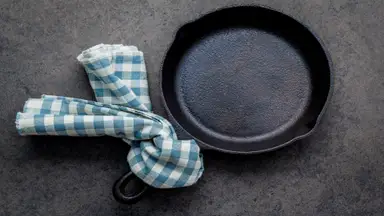 Dirty cast iron with blue and white checkered towel tied to the handle