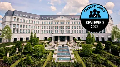 A large, grand hotel with lush gardens in front of it