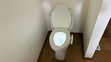 White toilet in front of white walls with the Kohler Dekoda installed in the right side, with the toilet bowl illuminated.