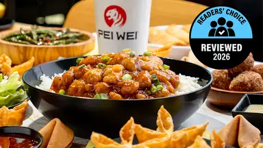 A close-up of a Pei Wei beef lo mein bowl with noodles, green beans, red peppers, and glazed beef on an orange branded background, with a Pei Wei cup visible and a Readers' Choice Reviewed 2026 badge.