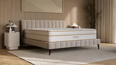 Saatva Classic innerspring mattress with Euro pillow top and gold trim on a beige upholstered bed frame in a warm wood-paneled bedroom.