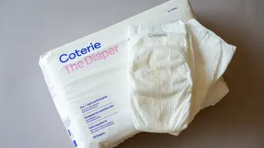 White Coterie The Diaper package with two diapers laying on top of it.