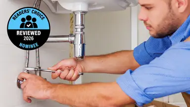 A person fixes a drain under a sink