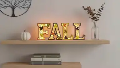 Home Depot Orange Rustic Lighted Fall Decor Sign LED on a wooden shelf hanging on a white wall.