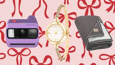 A purple camera, gold watch, and Ugg blanket on pink paper with red bows