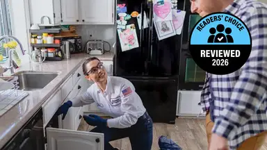 A person fixes a drain under a sink