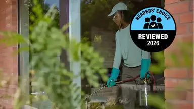 A pest control specialist using chemicals behind glass in a brick building