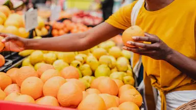 A person compares oranges at a grocery store.