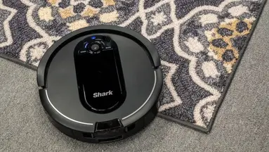A Shark IQ AV1010AE Robot Vacuum cleaning a carpet.