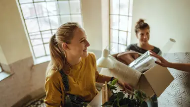 two women moving boxes up a staircase