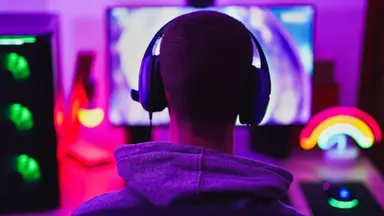 A person wearing headphones and sitting in front of a computer monitor