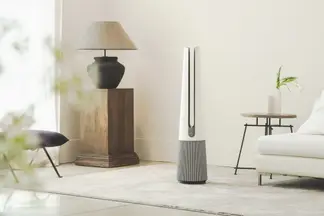 A tall, silver, needle-like air purifier stands in a modern living room