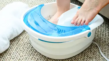 A pair of feet in a white and blue foot spa.