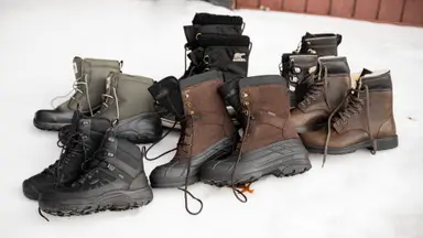 A wide selection of men's winter boots, sitting on a bank of snow.