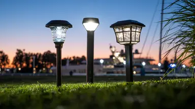 A row of outdoor solar path lights in a park, set against a sunset