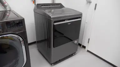 A gray Whirlpool dryer placed in a laundry room.