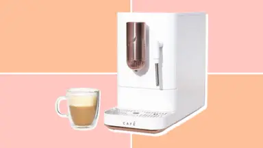 Café Affetto machine next to a latte in a glass mug, on a pink and orange backgorund.