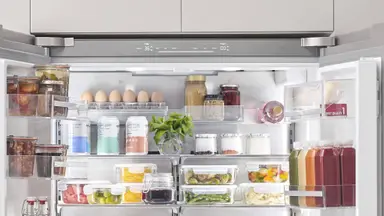 Open Bosch refrigerator showing lots of lovely food and beverages.
