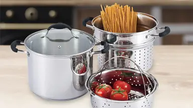 Three stainless steel pasta pots, along with three red tomatoes and uncooked spaghetti noodles