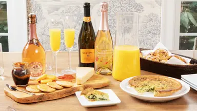 Spread of mimosas and brunch food on wooden table