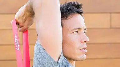 A man performing tricep extensions with a loop band.