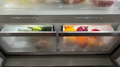 Two side-by-side Bosch crisper drawers slightly ajar, filled with produce