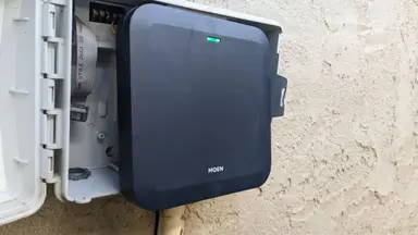 Moen Smart Sprinkler Controller attached to control box on exterior wall.