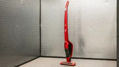 A red Electrolux Ergorapido standing upright in front of  a metallic background.