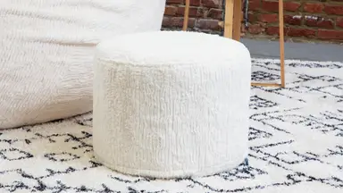 A close-up of Lovesac’s white furry ottoman.