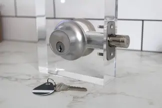 The Level Lock Plus Connect smart deadbolt set up on a test stand with a key and fob on the counter