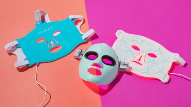 Three red light LED therapy masks on a pink background