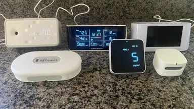 A group photo featuring the six indoor air quality monitors we tested sitting on a countertop