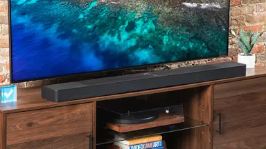 The LG S95TR soundbar sitting right below a flatscreen displaying an ocean.