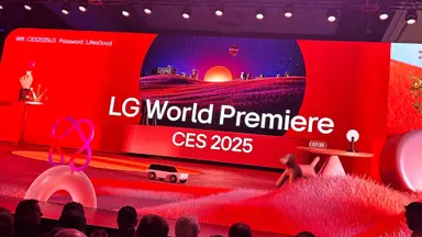 People sit in the audience looking at a stage with red lights and white writing for LG at CES 2025