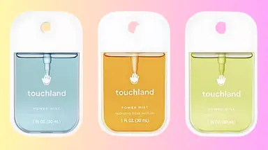 Three Touchland hand sanitizers on a colored background