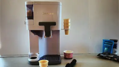 The Cuisinart Mix It In ICE-48 on a countertop surface with empty ice cream cones next to it.