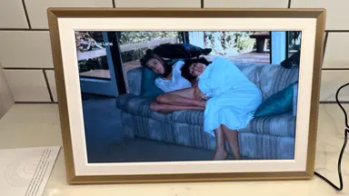 Two women laying on a couch in a picture on digital photo frame