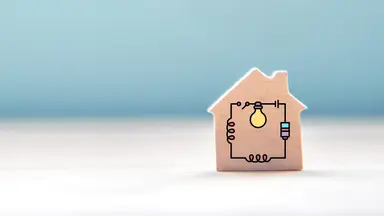 A small wooden toy house block with an electrical circuit graphic overlay