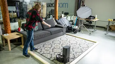 A woman testing a Roomba vacuum on the floor
