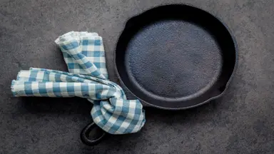 Dirty cast iron with blue and white checkered towel tied to the handle