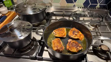 Alva Ceramic Cookware Set sitting on top of spider-burner stovetop with a pan cooking chicken.