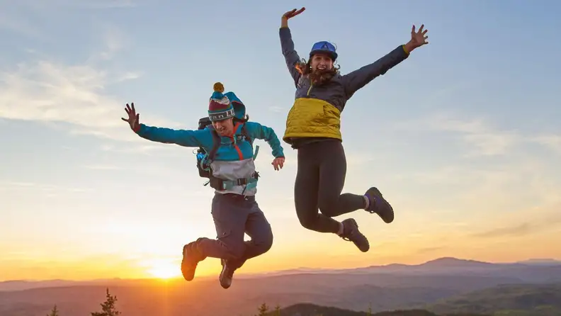 Two people jumping in L.L.Bean clothes on a mountain
