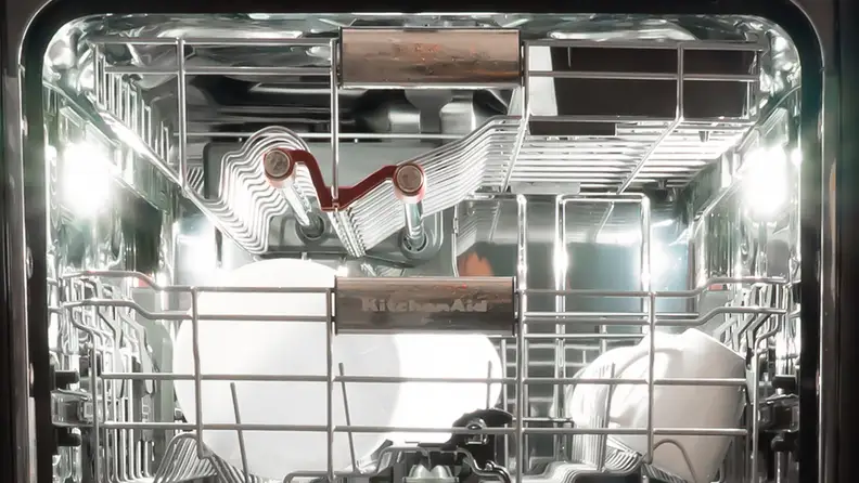 A close-up of the KitchenAid KDPM804KBS dishwasher with the door open, showing the two LEDs illuminating the interior. They're located about halfway into the device, along the left and right top edges.