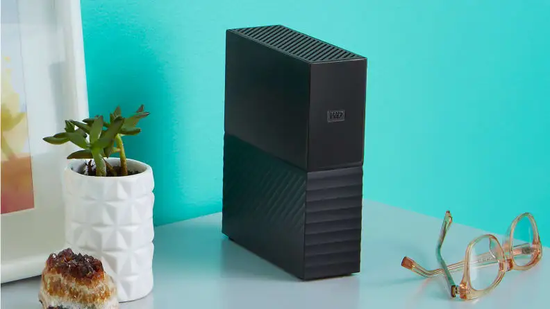 Two images of the same external, standing hard drive in black.