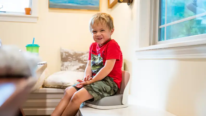 A boy sitting on a booster seat on a dining banquet.