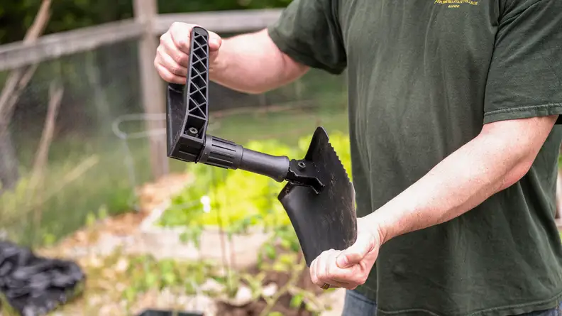 A person shoveling dirt with the Gerber Folding Spade