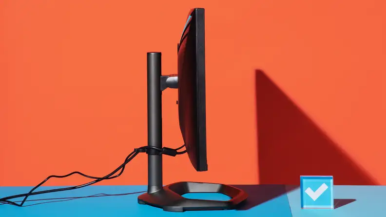 Side shot of the Cooler Master Tempest GP27Q gaming monitor on top of blue surface with wires coming out of back.