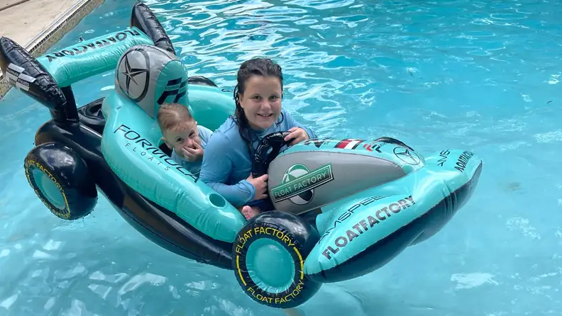 Two small children enjoying themselves on top of inflatable pool toy in water.