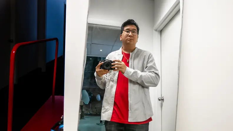 Man in long-sleeve shirt in front of mirror